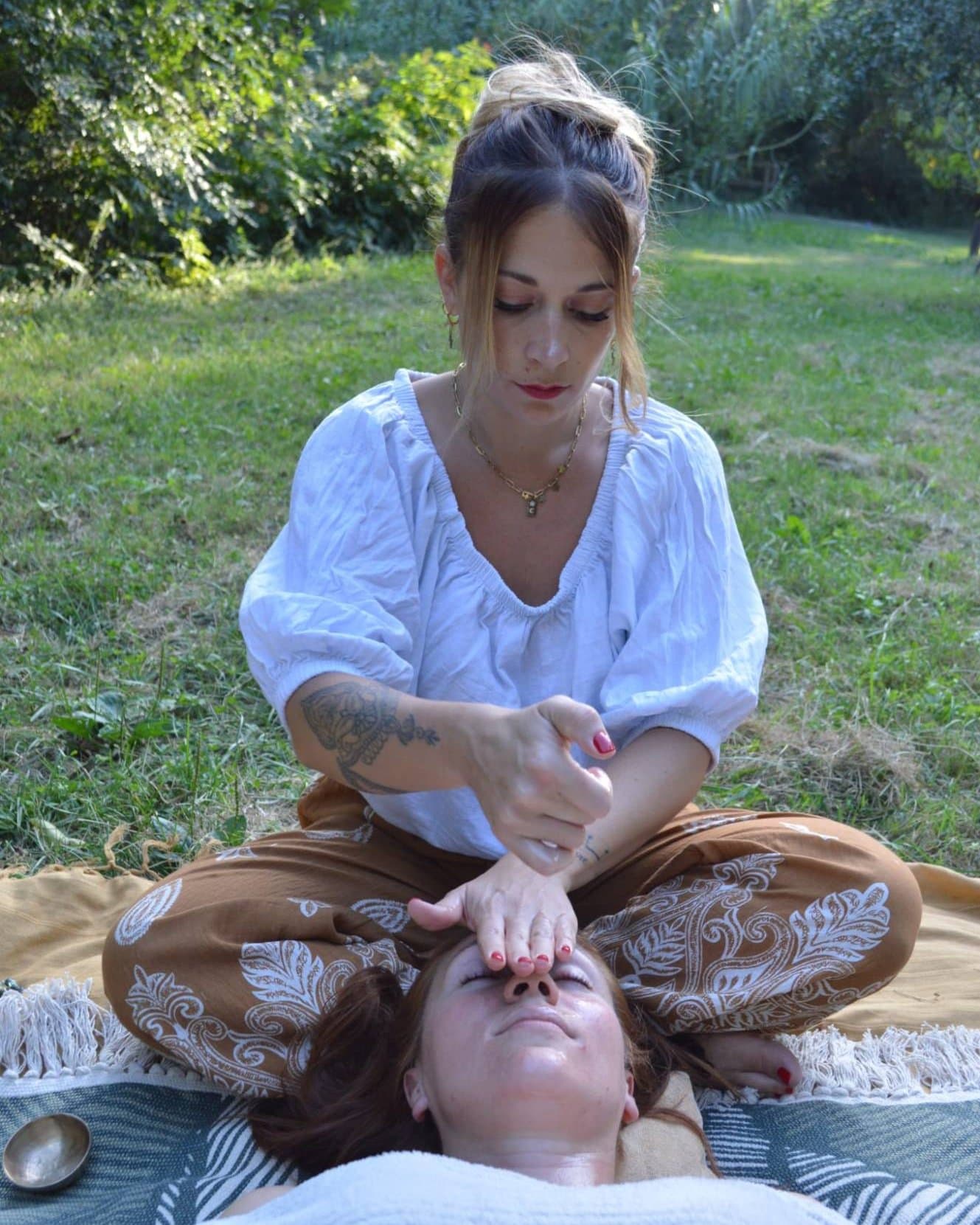 Annabelle guide une relaxation, les mains posées sur le visage d'une cliente allongée
